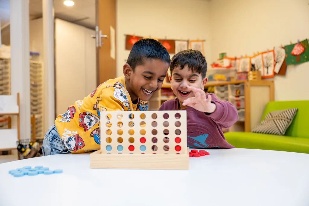 Twee lachende kinderen spelen vier op een rij